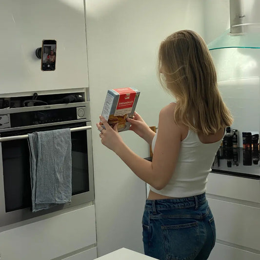 Pige filmer i sit køkken, med telefon